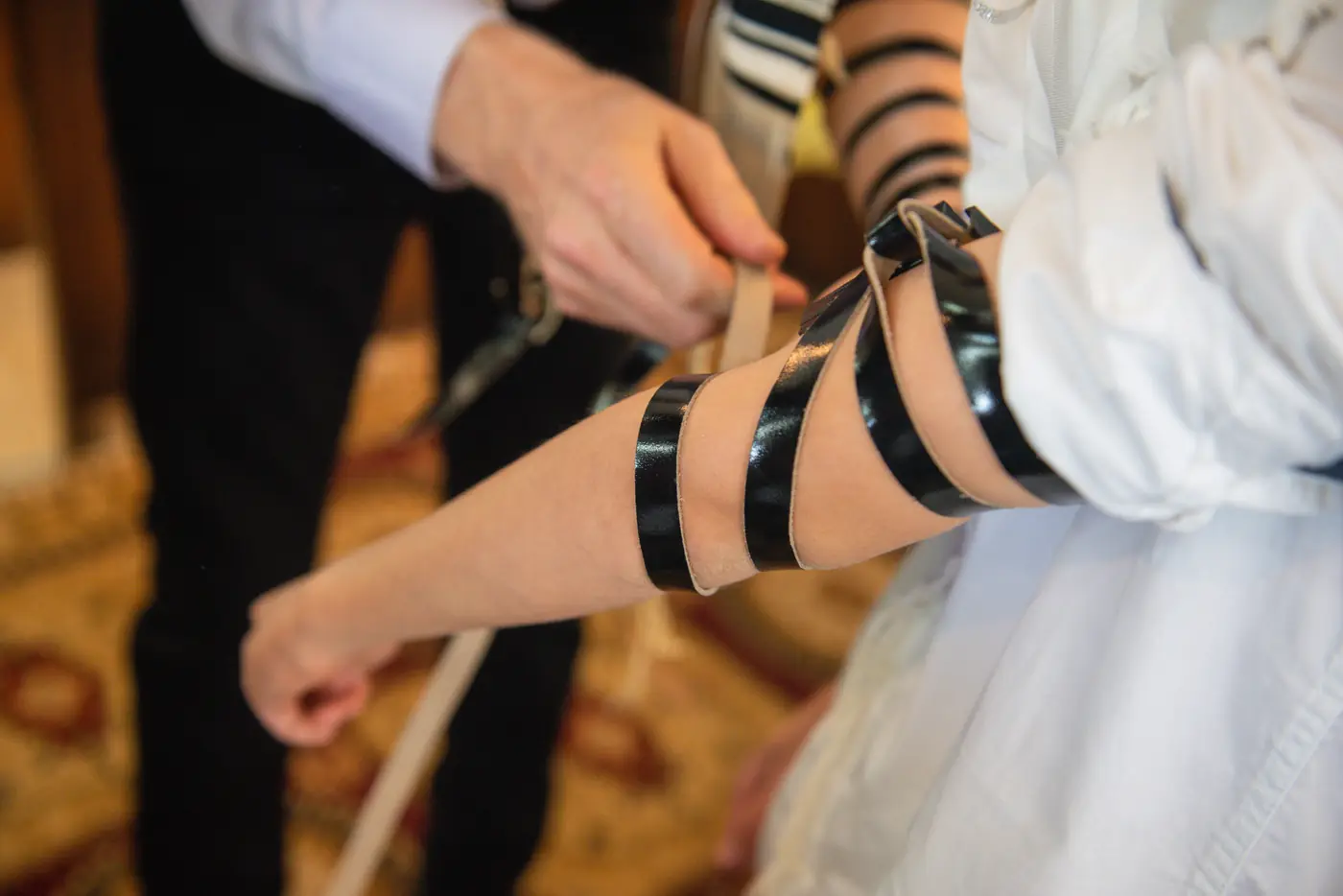 הנחת רצועות תפילין על היד בטקס עליה לתורה