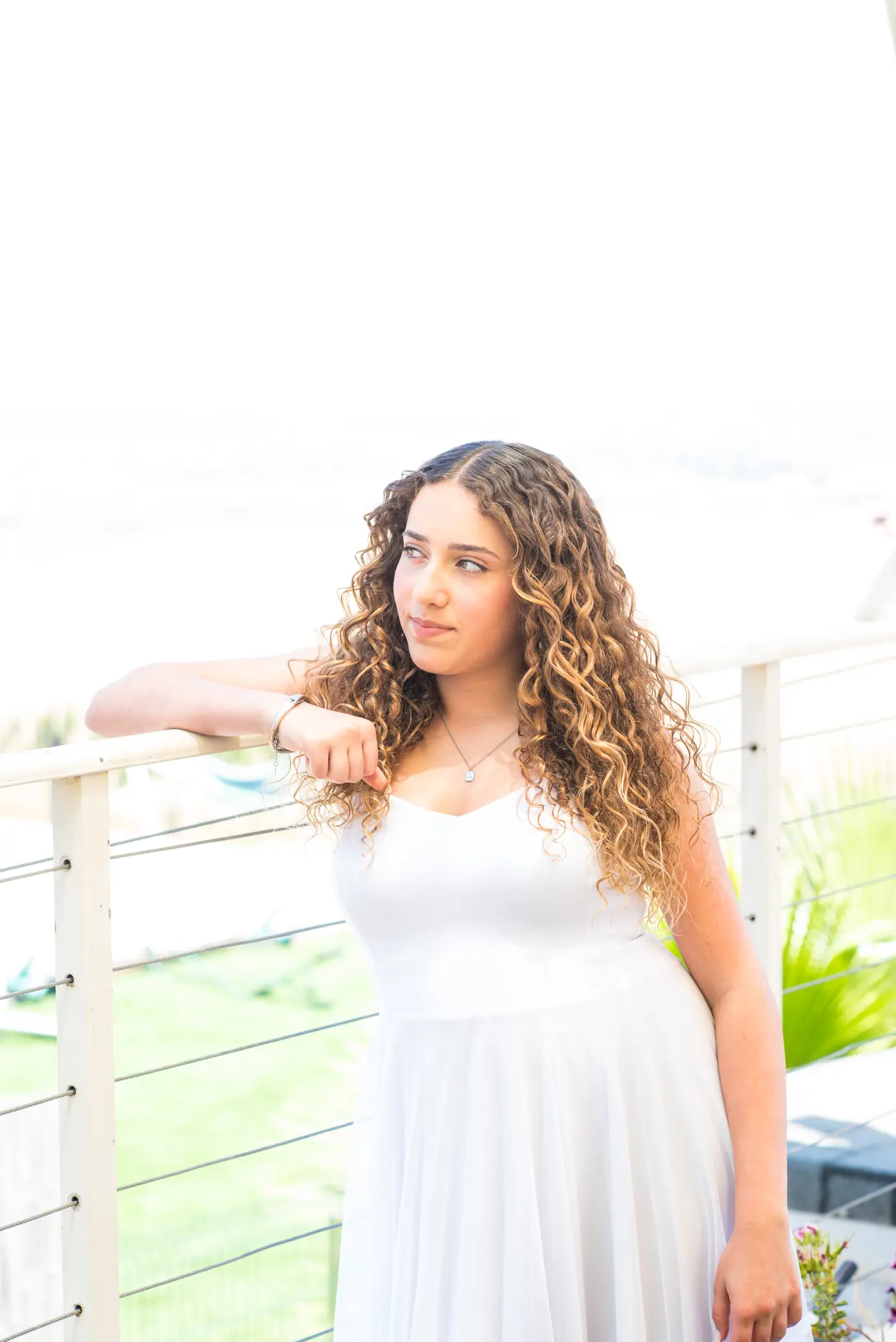 פורטרט חוגגת בת מצווה נשענת על מעקה, נוף פתוח ברקע