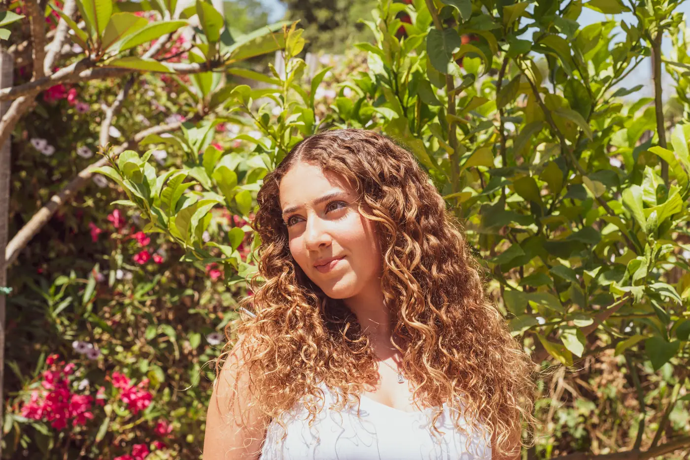 פורטרט חוגגת בת מצווה עם שיער מתולתל בין פרחים