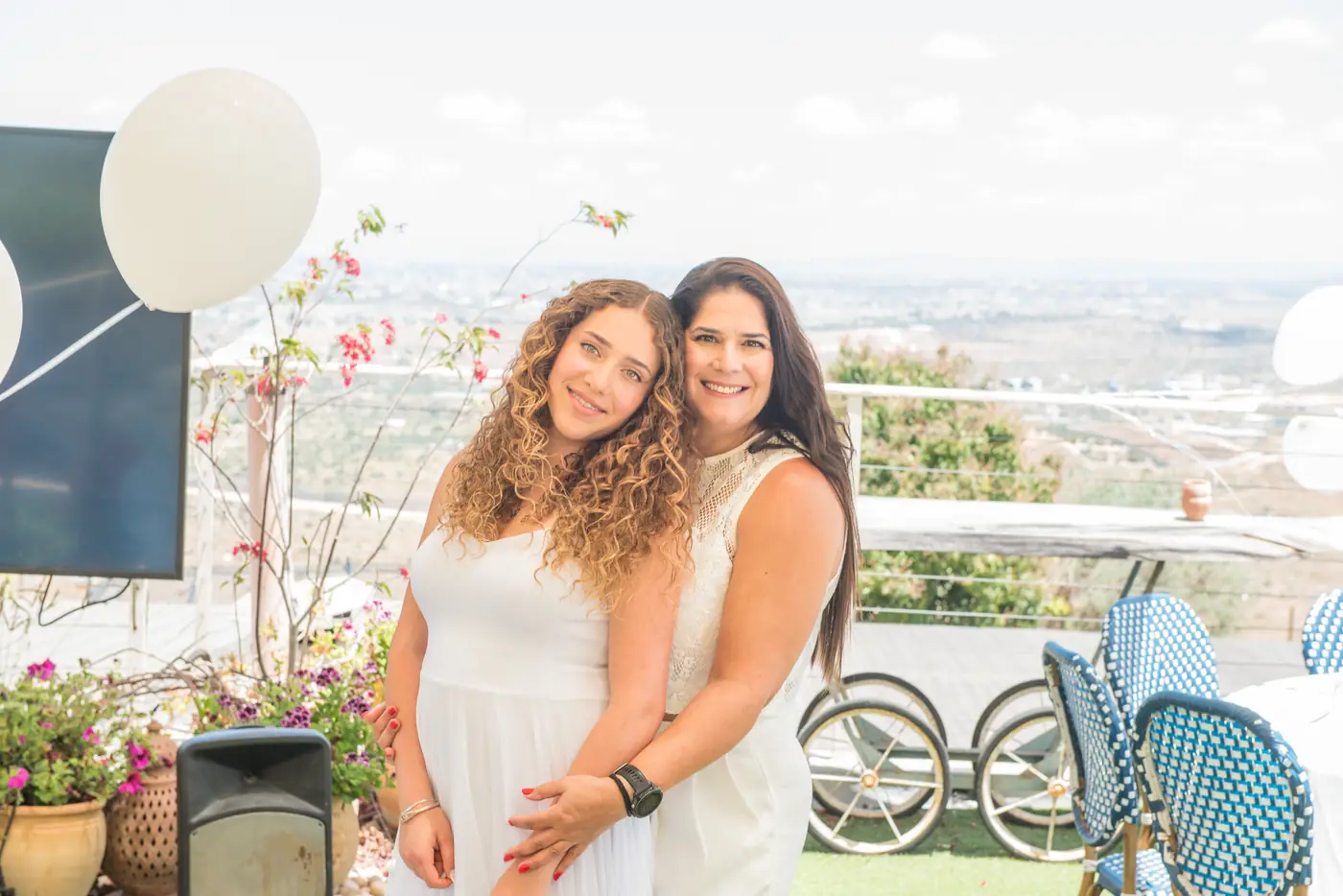 חיבוק חם בין אם לבתה החוגגת, נוף פתוח ברקע