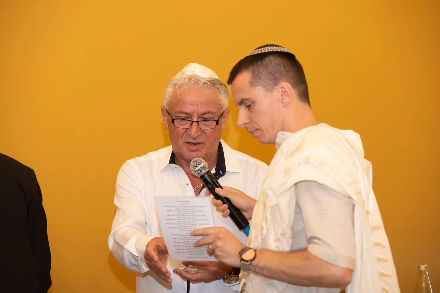 שני גברים בטליתות קוראים מדף ברכות בטקס